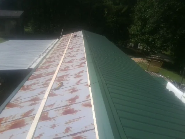 Old rusted panels beside newly installed green metal roofing — Wind Damage Roof Repair by Roofing Brothers in Eagle